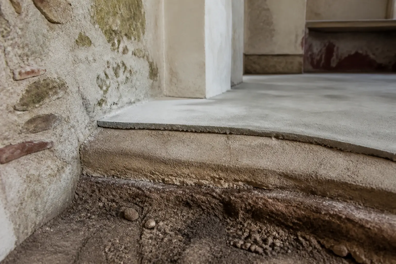 Dalle chaux dans une maison ancienne : coupe de sol respirant avec terre compactée, sous-couche à la chaux et mur en enduit ancien.