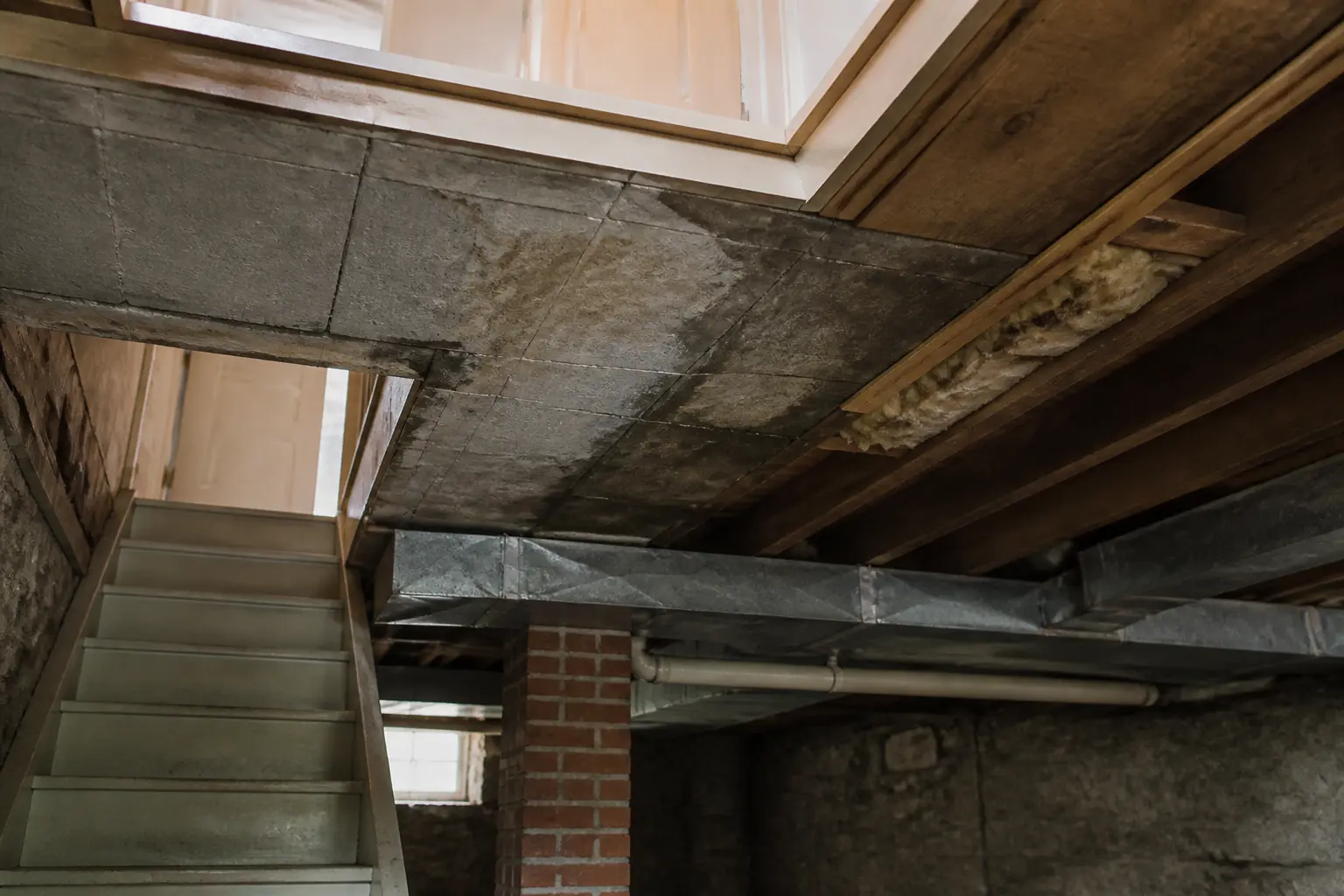 Inspection pour isoler le plafond du sous sol : plafond brut, solives apparentes, zones sèches et traces d’humidité.