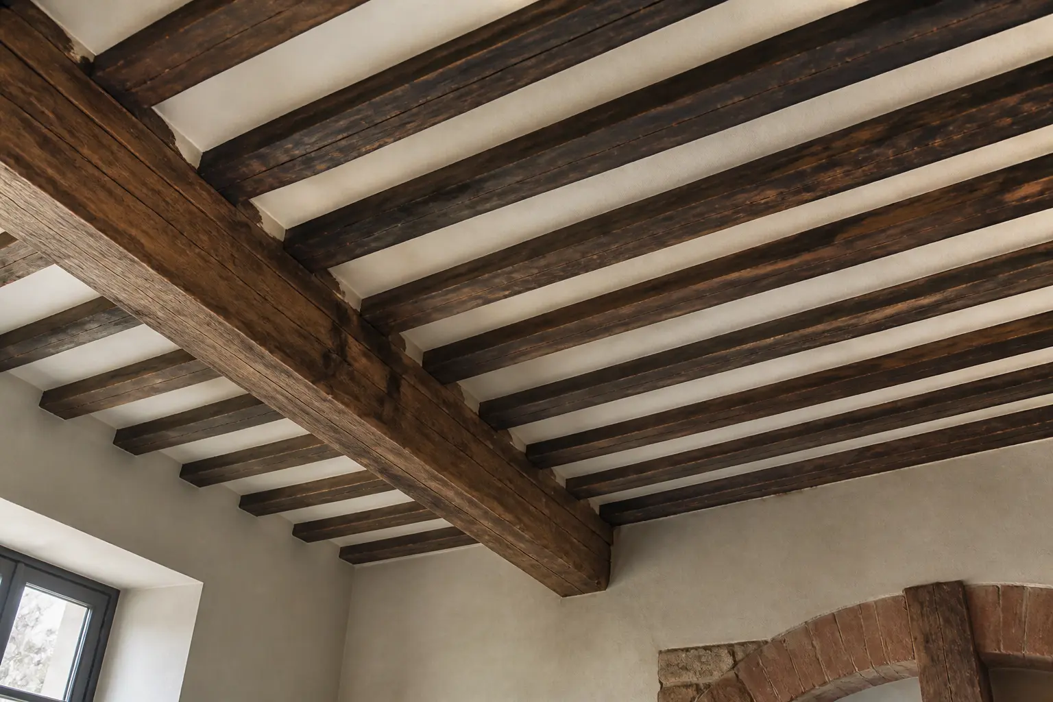Plafond à la française dans une vieille maison, poutres apparentes sombres et panneaux de plâtre clairs, vue en contre-plongée.
