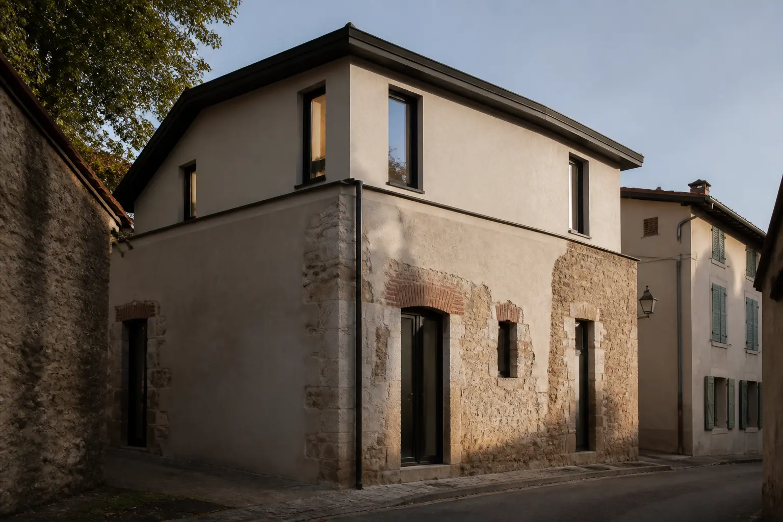 Surélévation maison ancienne : maison en pierre avec nouvel étage léger, toiture relevée et façade contrastée en rue résidentielle