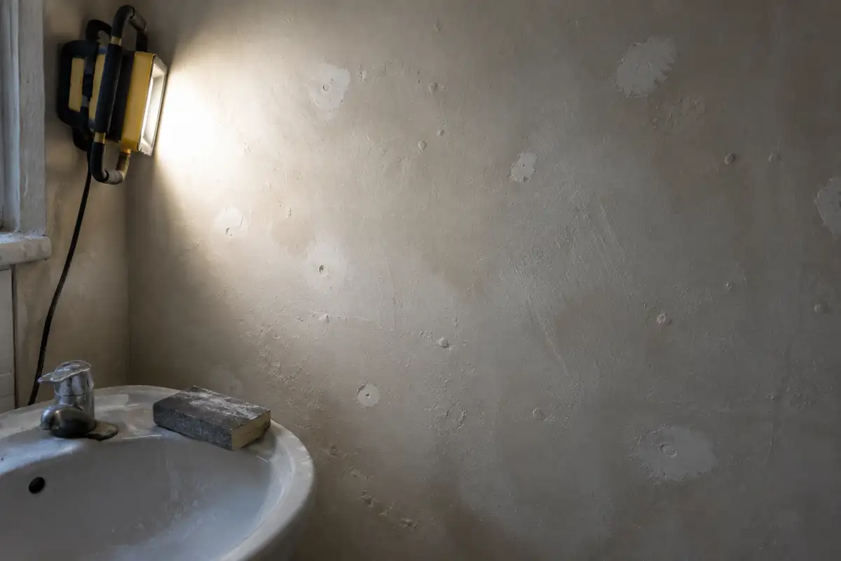Mur de salle de bain préparé, éclairé en lumière rasante qui révèle les défauts